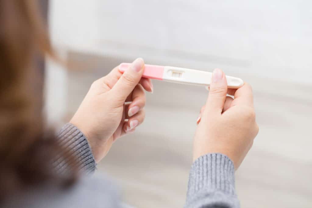 A closeup of a woman holding a positive pregnancy test.