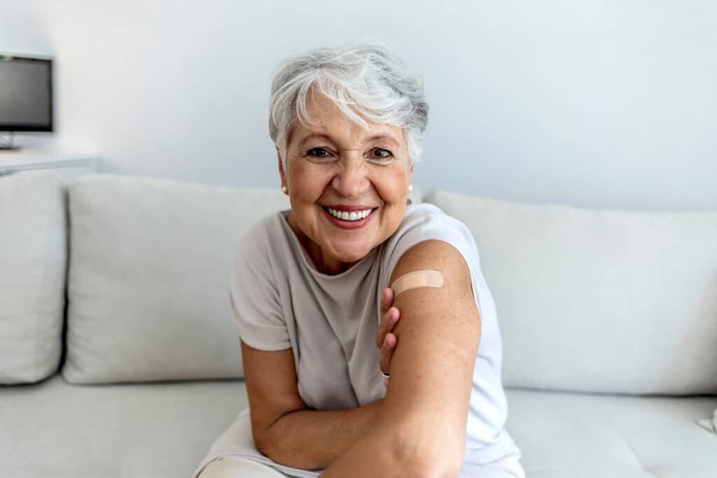 Portrait of a senior woman proudly showing her arm with bandage after getting vaccine.